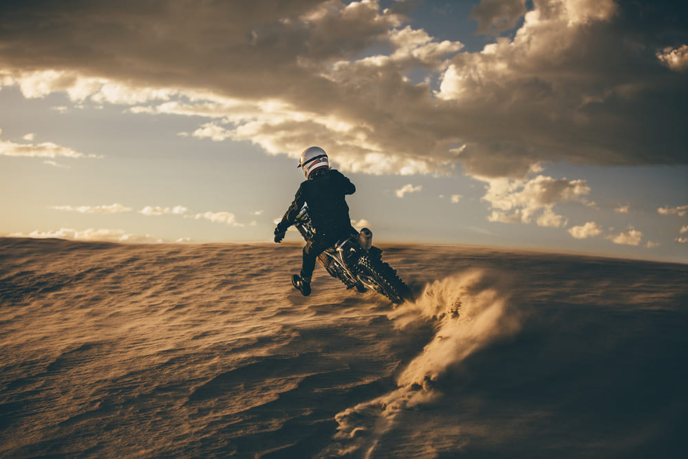 man wearing motorcycle gear and riding his bike in the desert