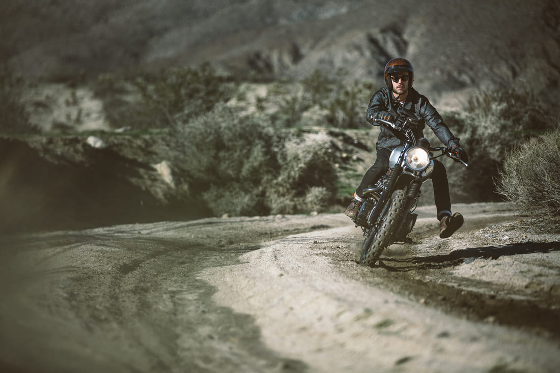 man wearing motorcycle gear riding bike on dirt a road