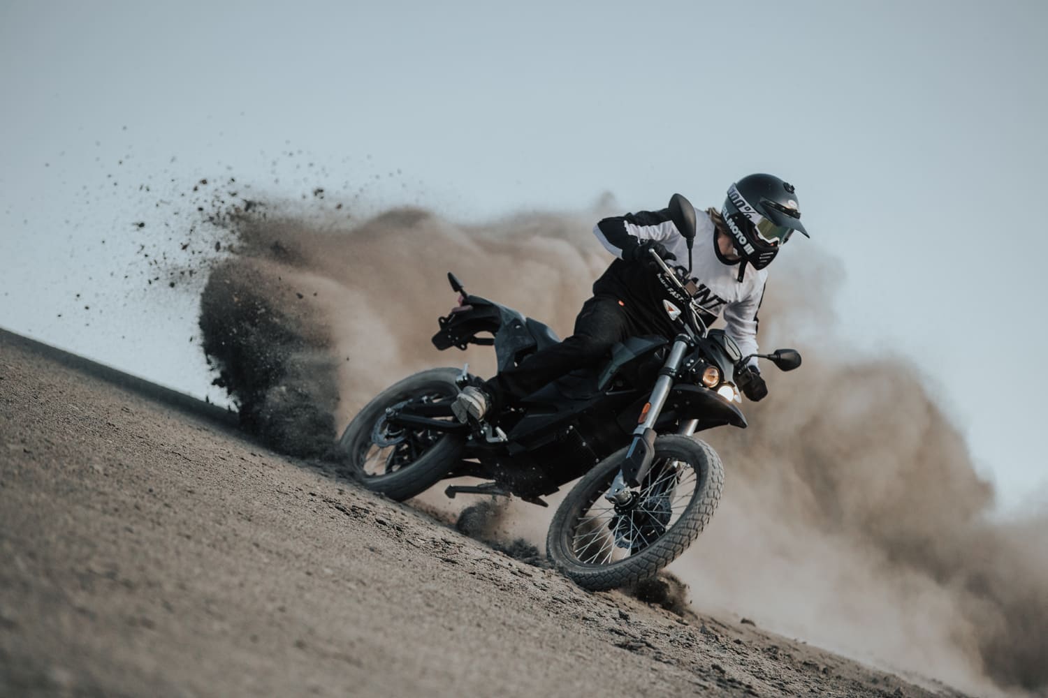 man riding a motorcycle in the sand and wearing moto gear
