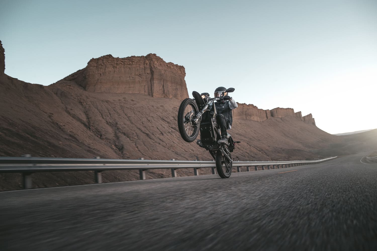 man doing a wheelie while riding a cycle  fast in the desert